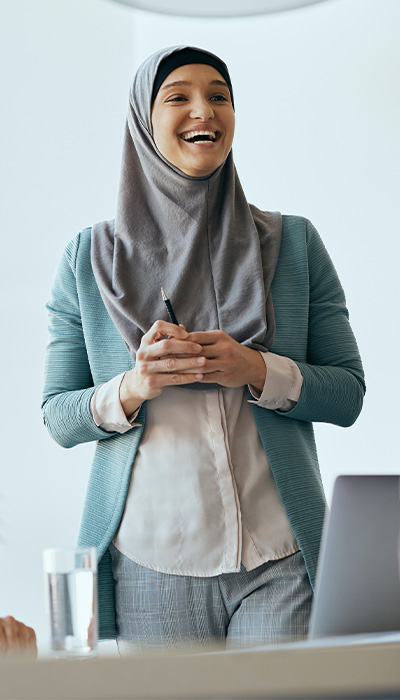 Photo of women smiling with gray hijab on and teal blazer 