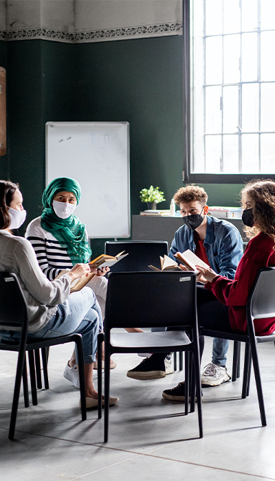 Four people sitting in a circle with mask on having a discussion