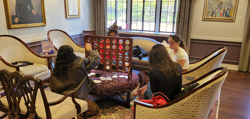 A group of young adults playing jumbo connect4 in a room